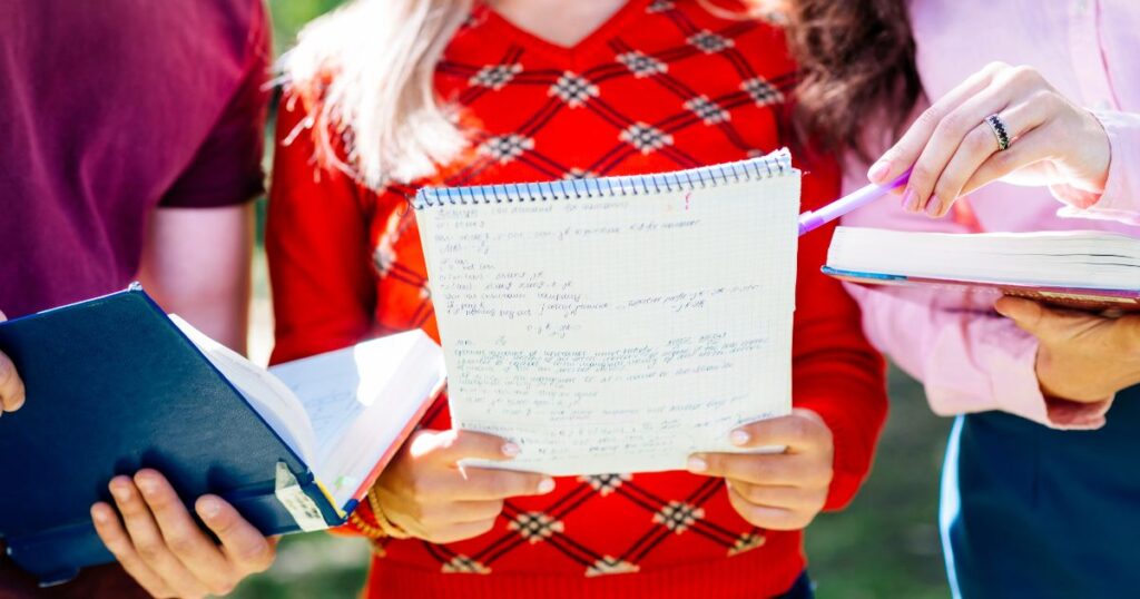 three students at henrietta barnett school writing on papers during a class activity