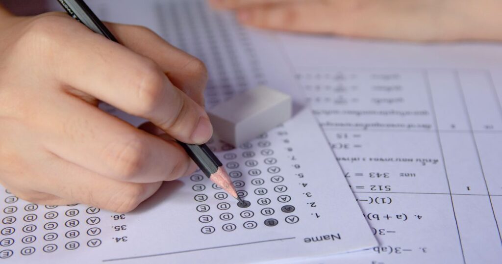 A person writing on a test paper with a pencil, highlighting differences between CEM and GL