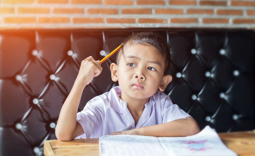 A young boy sitting at a table with a pencil in his hand, representing the differences between CEM and GL
