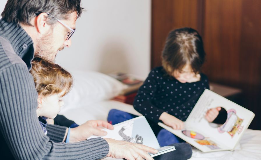 Father reading bedtime story to children on bed